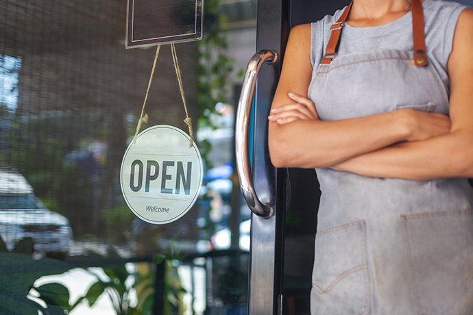 The woman is a waitress in an apron, the owner of the cafe stands next to door with open sign